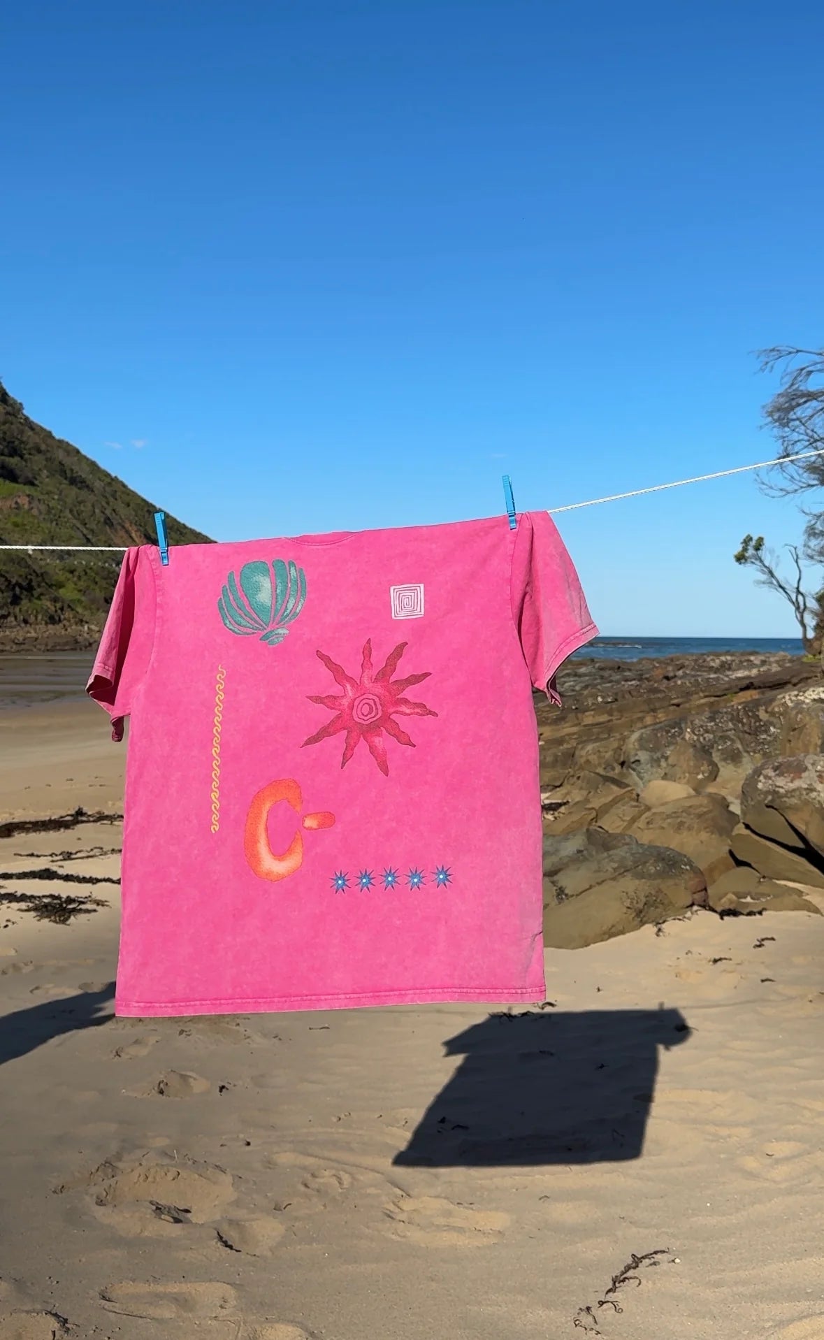 Zamimi Swell Tee in pink hanging on a line at the beach